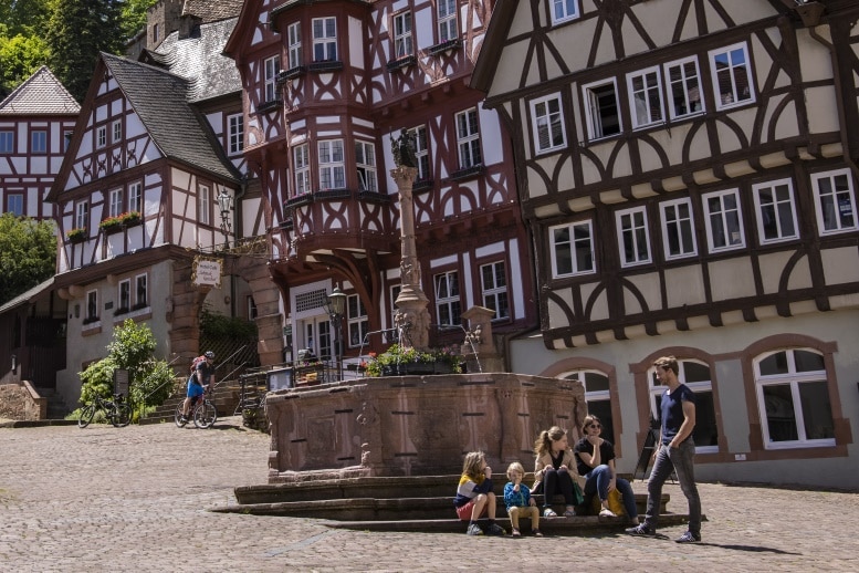 Eine Familie sitzt auf den Stufen zum Marktbrunnen am Marktplatz in Miltenberg