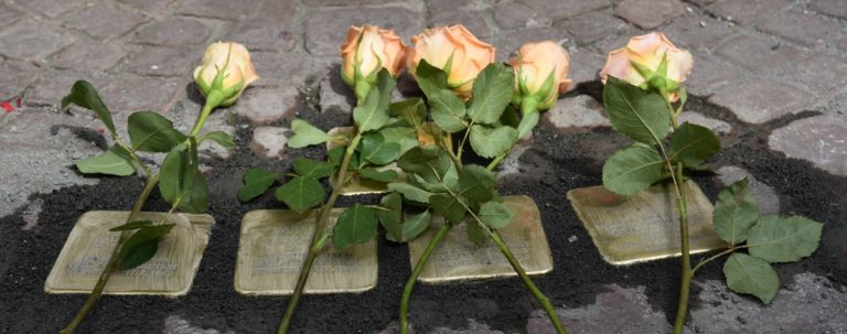Vier frisch verlegte Stolpersteine mit Rosen bei der Stolpersteinverlegung 2017