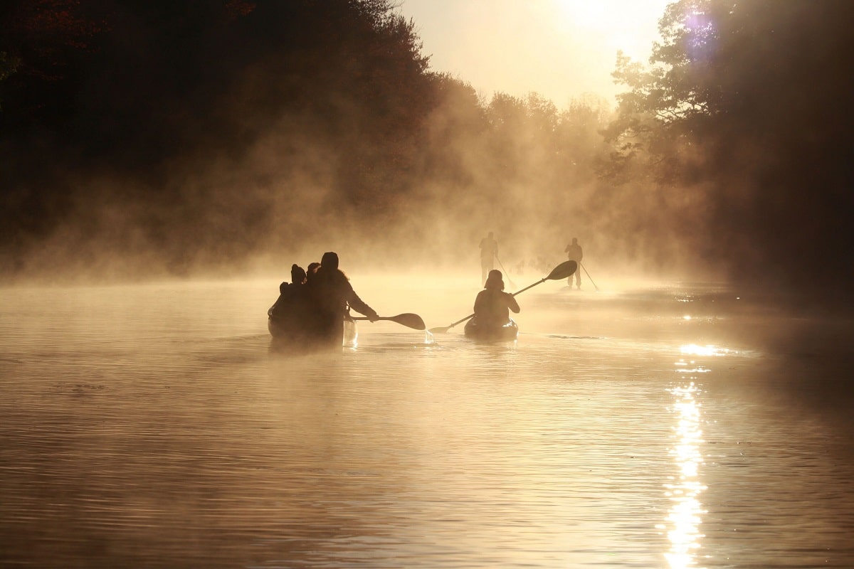 Ein Kanu, ein Kajak und zwei Stand Up-Paddler im Morgendunst