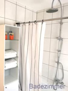 Badewanne mit Duschvorhang und Duschkopf im Badezimmer der Ferienwohnung Dörr in Bürgstadt