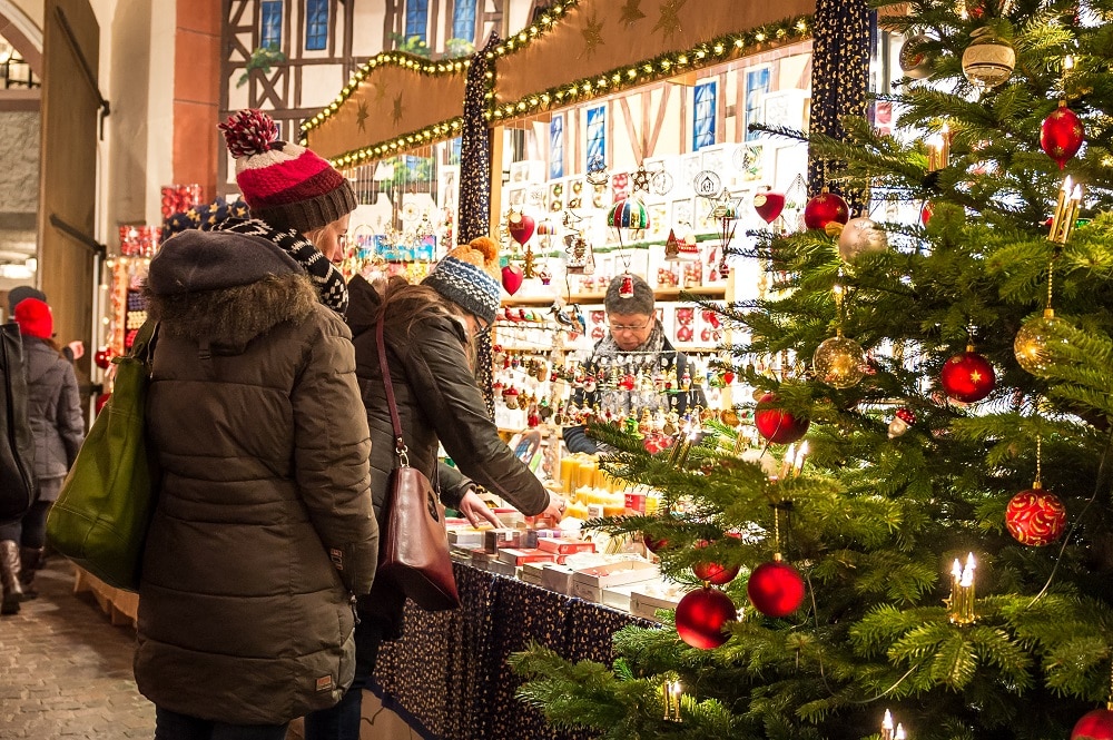 Gäste schauen sich auf dem Weihnachtsmarkt das funkelnde Sortiment der Aussteller im Alten Rathaus an.