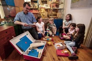 Ein Vater und vier Kinder sitzen im Museum beschäftigen sich mit dem Museumskoffer