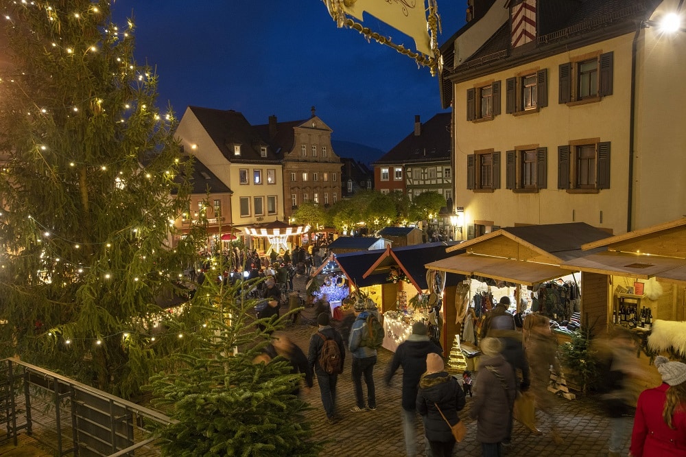 Blick auf den Weihnachtsmarkt am Marktplatz. Zu sehen sind Buden von verschiedenen Ausstellern und ein Kinderkarrussel.