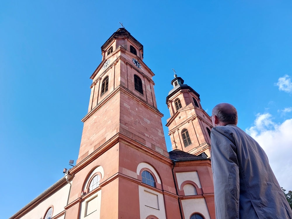 Der Gästeführer Werner Wagner schaut ehrfürchtig die Kirchtürme der Jakobuskirche in Miltenberg hinauf
