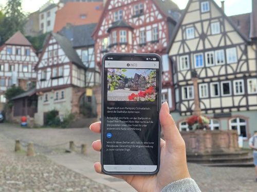 Frau hält Handy in der Hand und öffnet die digitale Stadtrallye über Actionbound