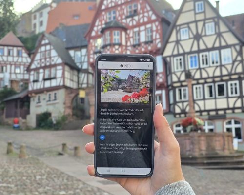 Frau hält Handy in der Hand und öffnet die digitale Stadtrallye über Actionbound