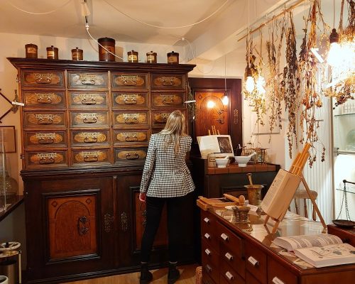 Eine Besucherin bewundert den historischen Apothekenschrank aus verschiedenen Hölzern im Apothekenmuseum Miltenberg