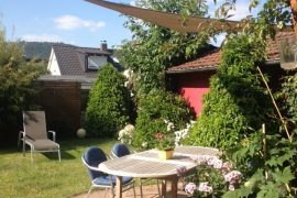 Blick hinaus in den Garten. Alles ist grün und ein Liegestuhl ist zu sehen.