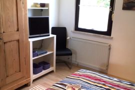 Schrank, daneben ein kleines Regal mit Fernseher in der Ferienwohnung Dörr in Bürgstadt