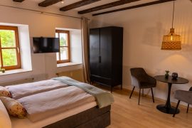 Doppelbett, Kleiderschrank und Essbereich in der Ferienwohnung an der Mainpromenade in Miltenberg