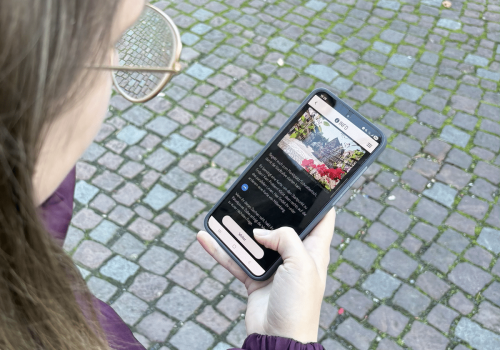 Frau hält Handy in der Handy und öffnet die digitale Stadtrallye