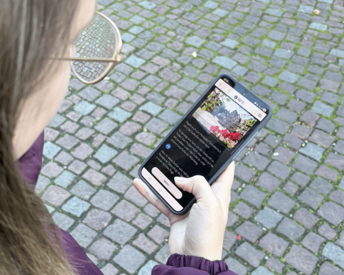 Frau hält Handy in der Handy und öffnet die digitale Stadtrallye