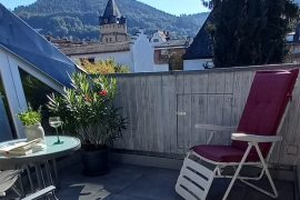 Sonniger kleiner Balkon mit einem Liegestuhl