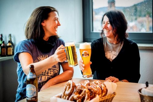 Zwei Damen trinken Bier und essen Brezel