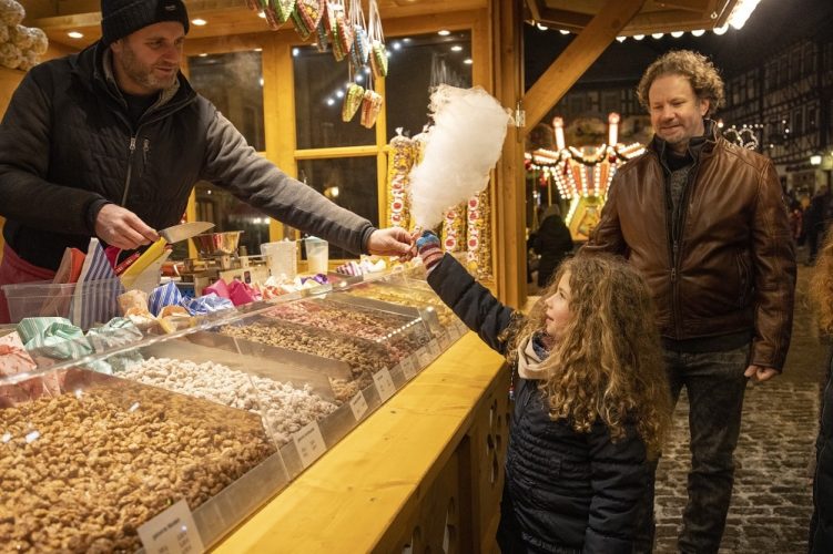 Kleines Mädchen bekommt von einem Aussteller eine leckere Zuckerwatte gereicht